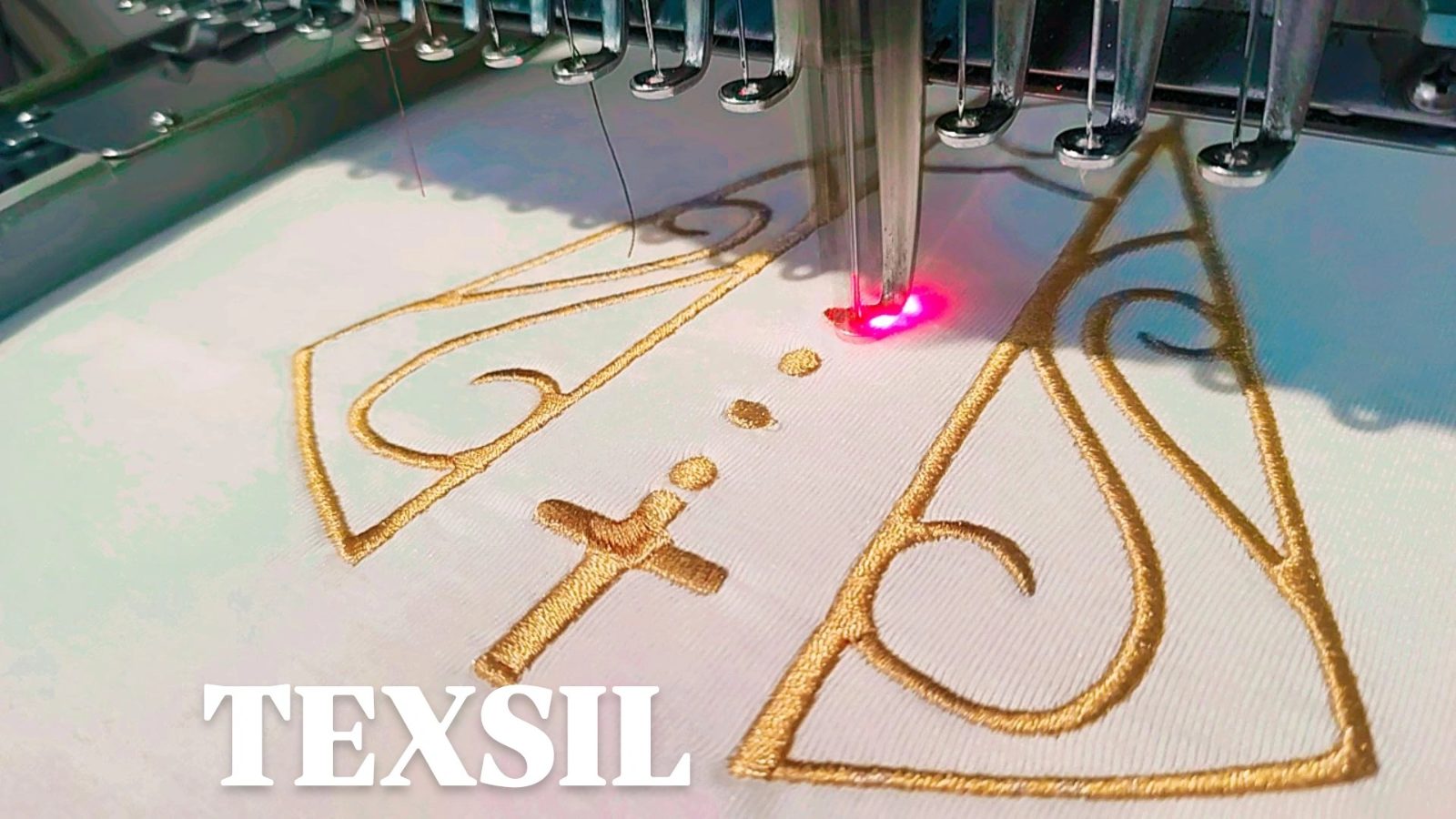 Máquina bordadora industrial cosiendo el logo de TEXSIL en hilo dorado